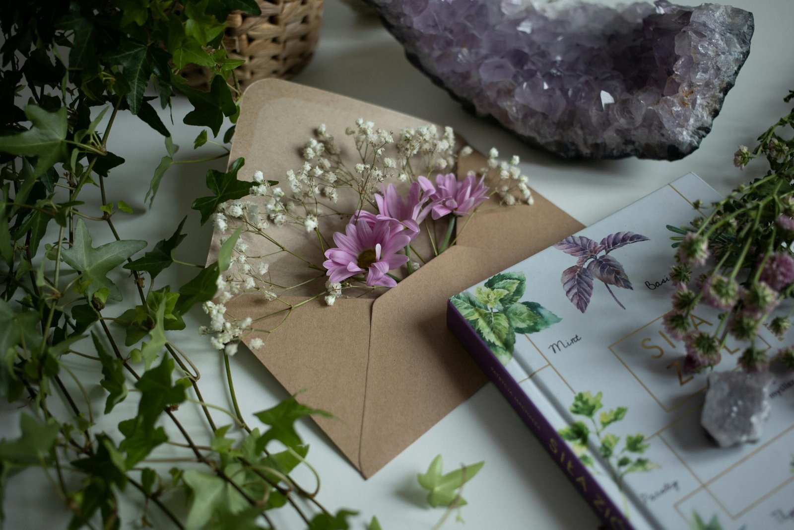 A beautiful flat lay of flowers, amethyst, and a botanical book on a table.