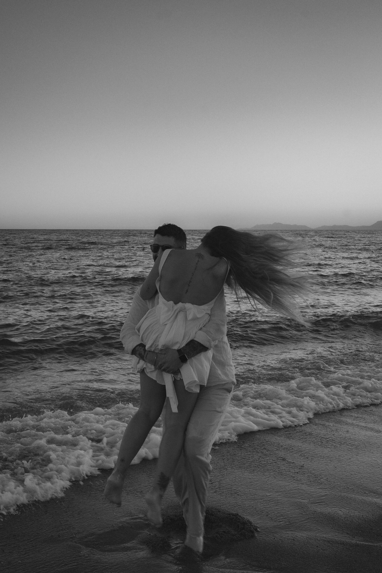 A couple shares a romantic moment at sunset on a serene Antalya beach in Türkiye.